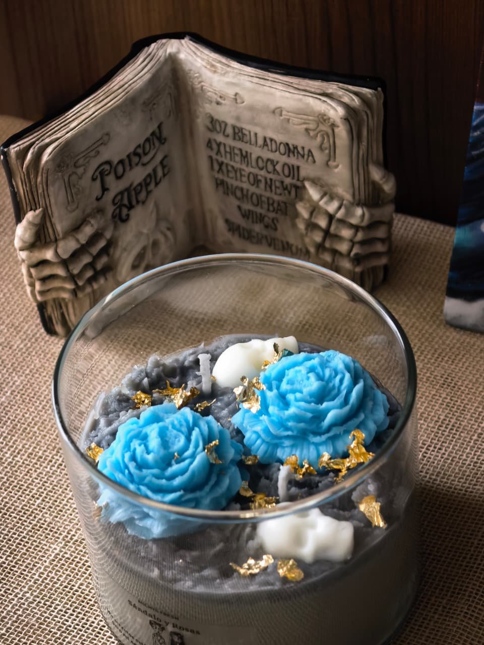Detalle en primer plano de la superficie de la vela inspirada en Emily con flores azules y pequeñas calaveras decorativas de cera.